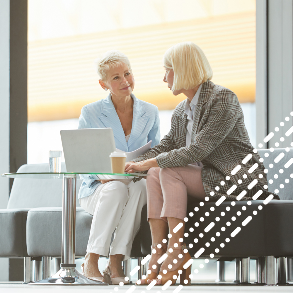 two business women chatting on sofa