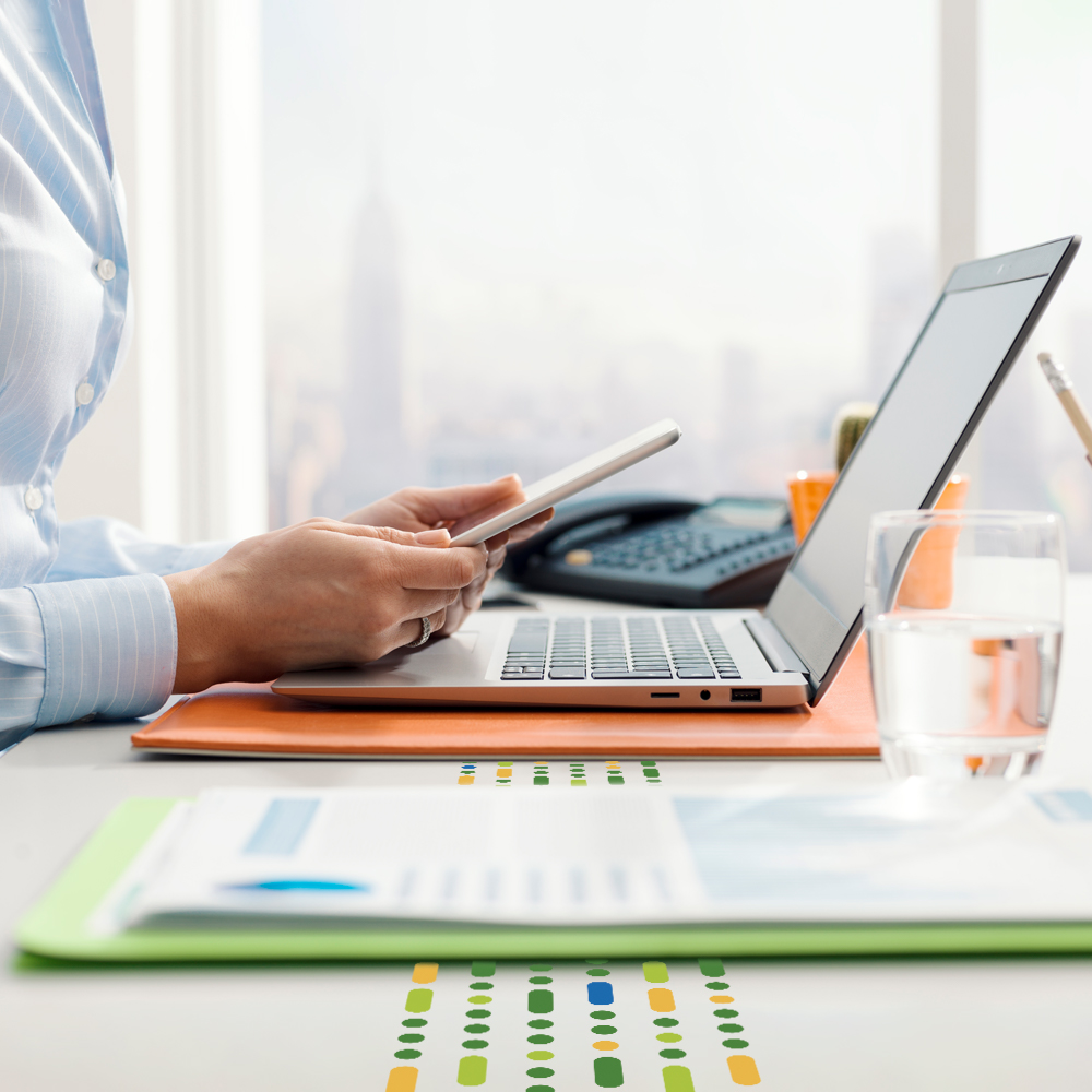 female looking at mobile in front of laptop