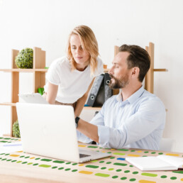 male and female discussing paperwork in front of laptop