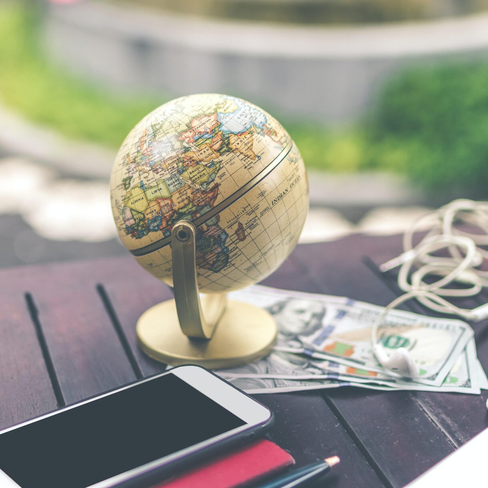 Globe, money, headphones, phone on a table