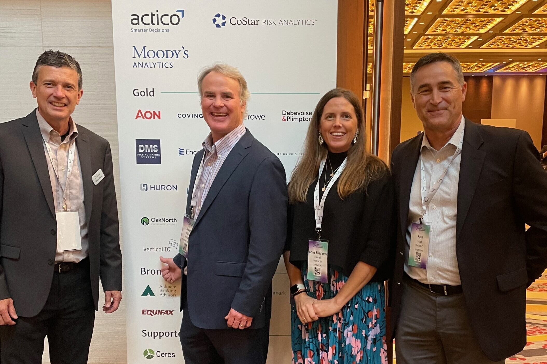 vertical iq team stood in front of sponsors sign