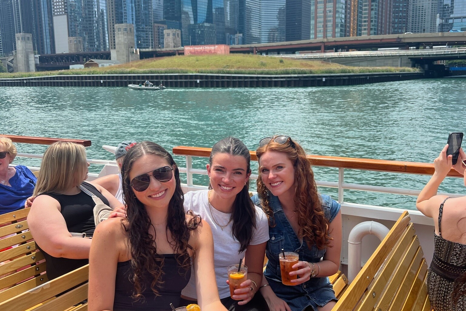 Group of three women on a boat in the Chicago river with the city in the background