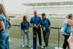 Three people standing on a field smiling at the camera