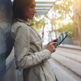 Woman playing on an ipad in a fall coat