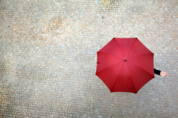 Red umbrella above cobblestone