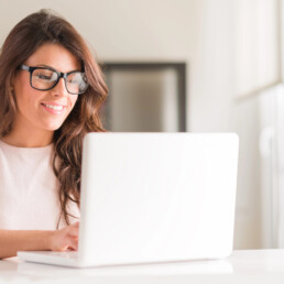 Woman wearing black glasses smiling at her computer